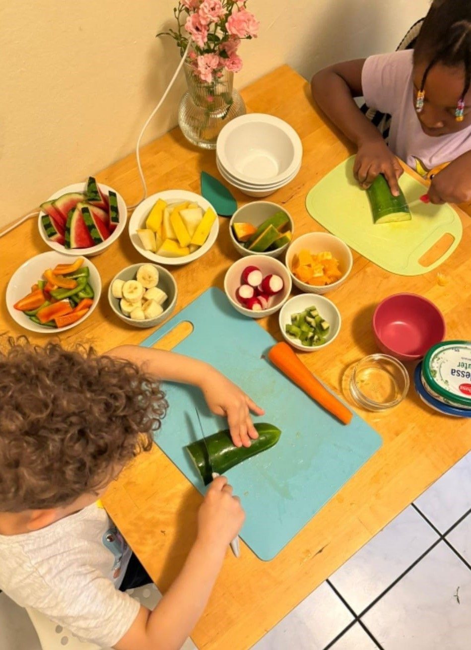 Kinder schneiden gemeinsam frisches Obst und Gemüse