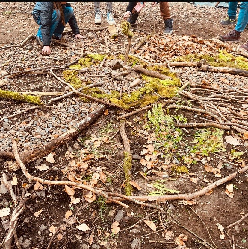 Kinder gestalten ein Naturbild aus Ästen und Moos im Wald